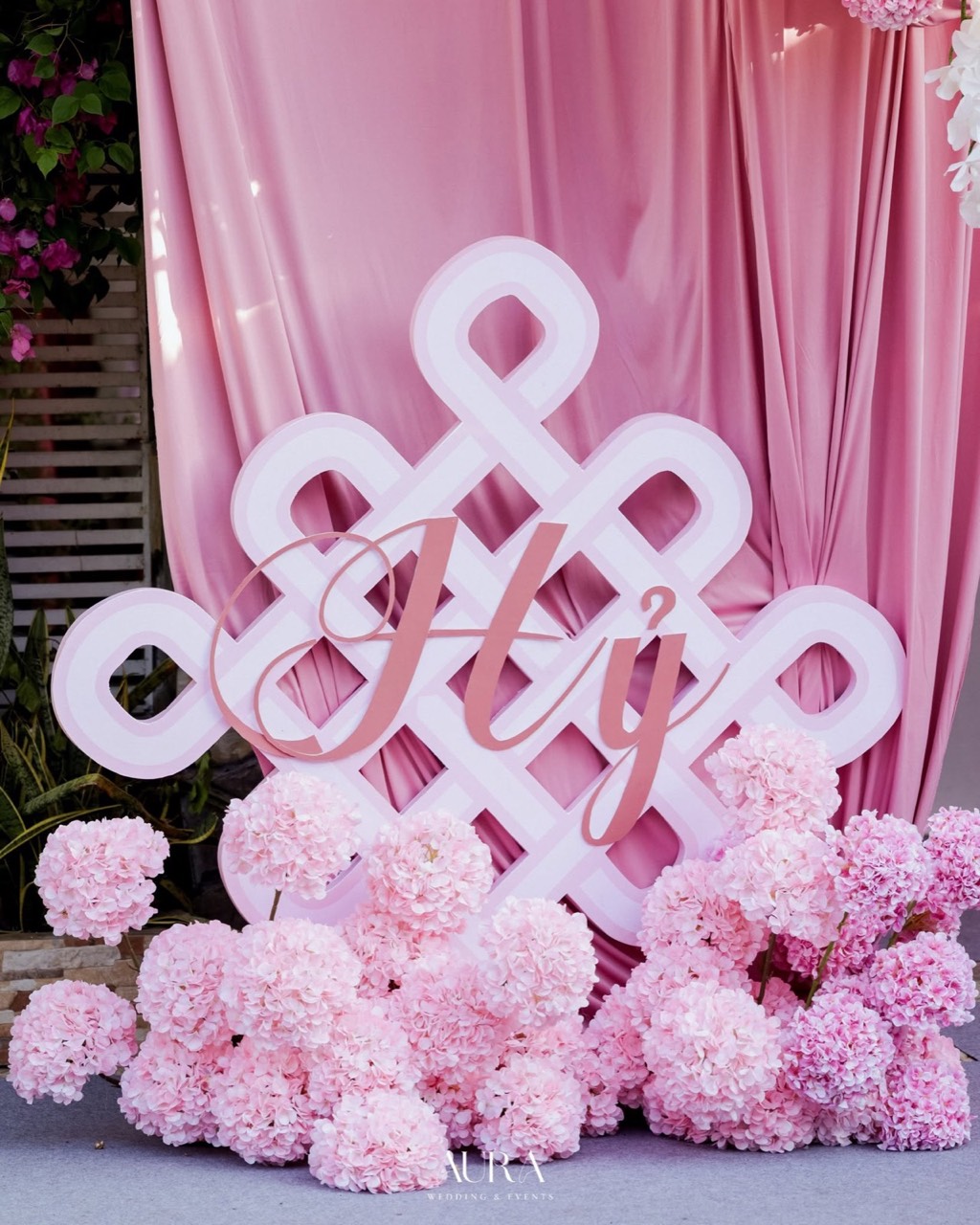 Chữ Hỷ nút thắt trắng hồng trên nền vải satin hồng, chân đế phủ kín cẩm tú cầu hồng
