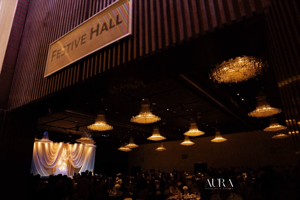 Biển Festive Hall và sảnh tiệc dưới đèn chùm, sân khấu rèm ngà sáng ở cuối sảnh